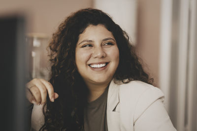 Happy young businesswoman looking away at office