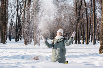 A girl in glasses and warm clothes throws snow in the winter forest. wellness.