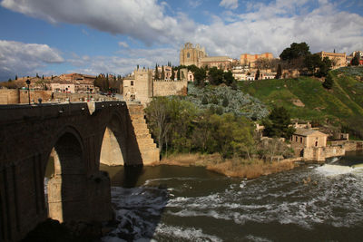 Bridge over river against cloudy sky