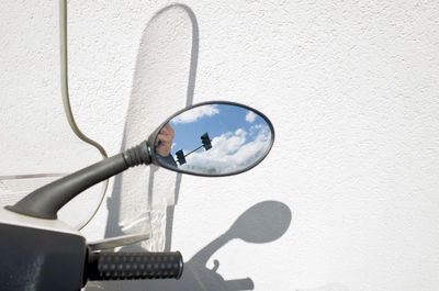 Cropped image of scooter side-view mirror against white wall
