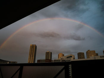 Low angle view of rainbow over buildings in city