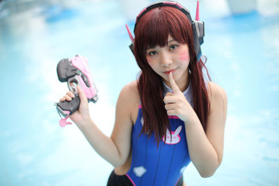 Portrait of smiling young woman drinking water while standing against sky