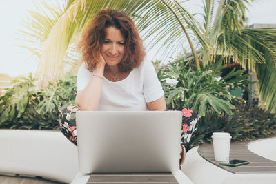 Smiling woman using laptop while sitting on table