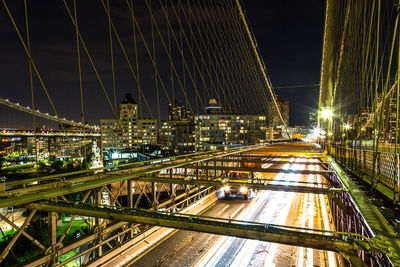 Illuminated bridge in city against sky at night