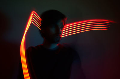 Blurred motion of man standing against illuminated light trails