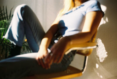 Midsection of woman relaxing on chair at home