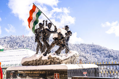 Statue on snowcapped mountain against cloudy sky