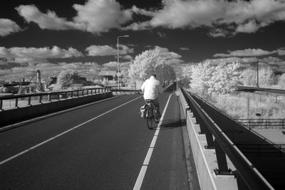 Rear view of man riding bicycle on road in city