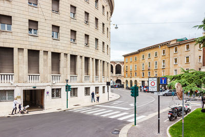 Road by buildings in city against sky