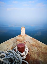 Wooden post in sea against sky