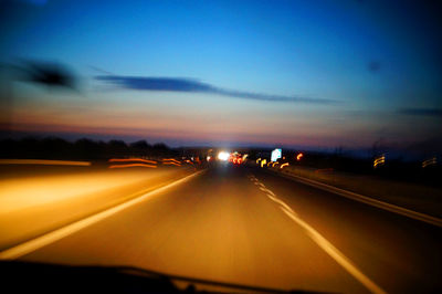 Cars on road against sky during sunset