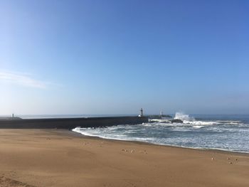 Scenic view of beach against clear blue sky