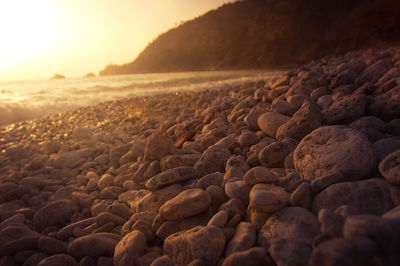 Rocks on beach against sky during sunset