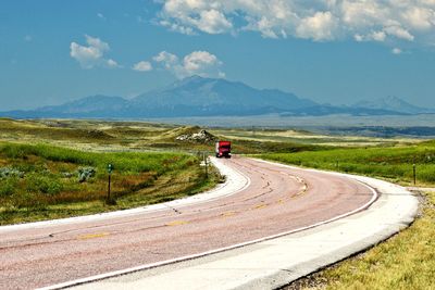 Vehicle on road amidst landscape against sky