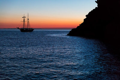 Silhouette boat sailing on sea against sky during sunset