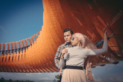 Young couple standing against sky