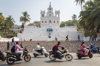 People on motorcycle against sky in city