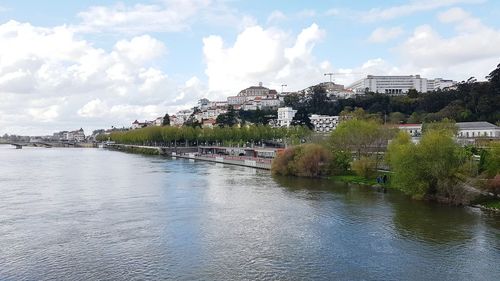 Scenic view of river by buildings against sky