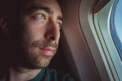 Thoughtful man looking through window in airplane