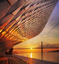 Bridge over sea against sky during sunset