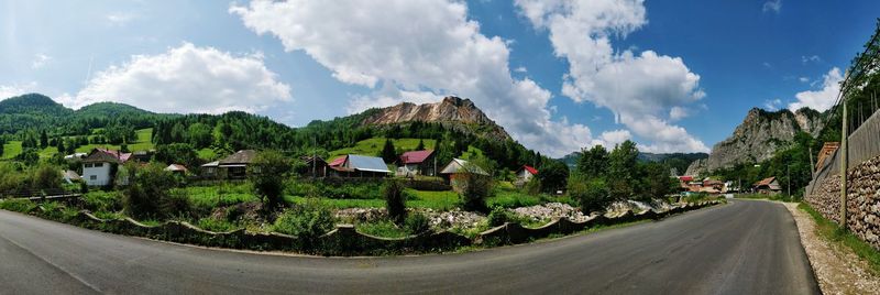 Panoramic view of road amidst trees and mountains against sky