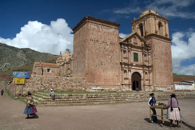 People at historic building against sky