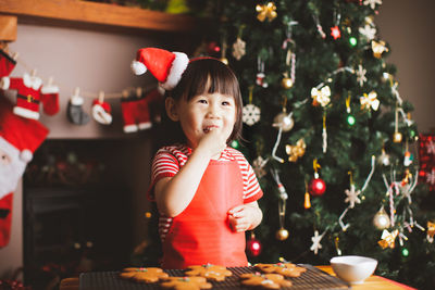 Girl eating cookies on table during christmas