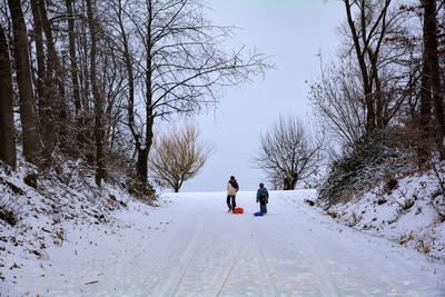 Boy and girl with sled walking on snow covered land