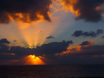 Scenic view of sea against dramatic sky during sunset