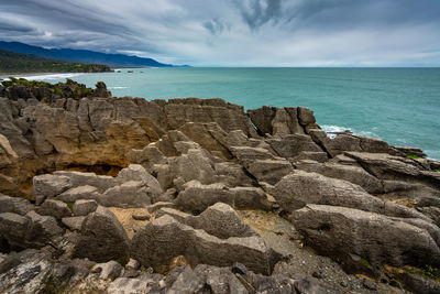 Scenic view of rocks on beach against sky