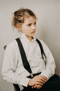 Girl sitting on chair against wall