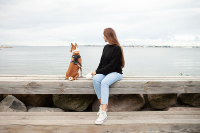 Rear view of woman sitting on railing