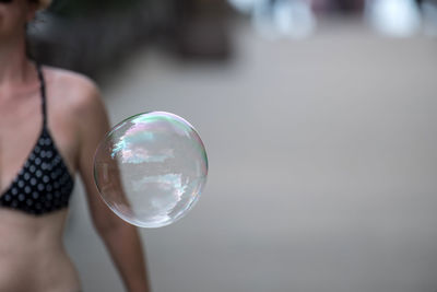 Midsection of woman with bubble flying outdoors