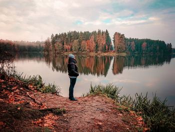 Man standing by lake against sky