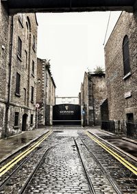 Empty railroad tracks by buildings against sky