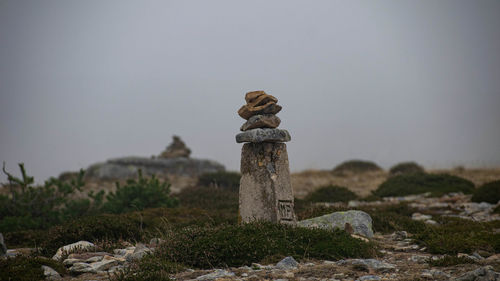 Stack of stones on field against sky