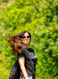 Young woman standing against plants