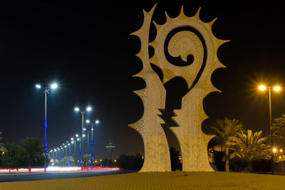 Illuminated street light against building at night