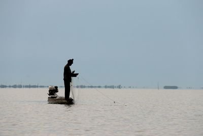 Man working in lake against clear sky