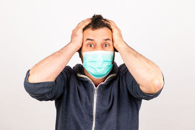 Portrait of man covering face against white background