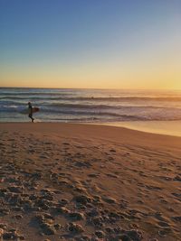 Scenic view of beach against clear sky during sunset