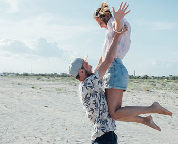 Low section of women on beach against sky