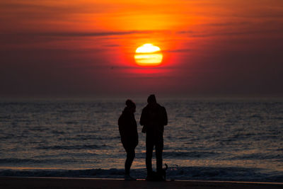 Silhouette people on beach during sunset