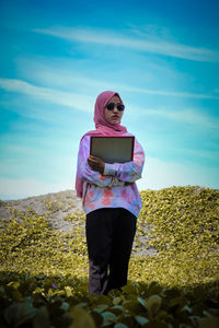 Portrait of young woman using phone while standing on land