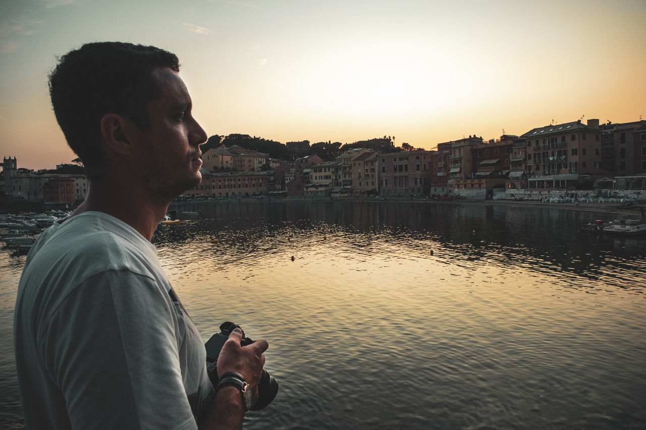 architecture, water, one person, real people, building exterior, sky, built structure, young men, sunset, lifestyles, young adult, side view, standing, leisure activity, nature, city, men, casual clothing, outdoors