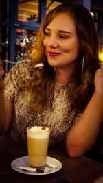 Smiling young woman looking away while sitting in restaurant