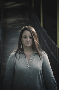 Portrait of beautiful young woman standing against curtain