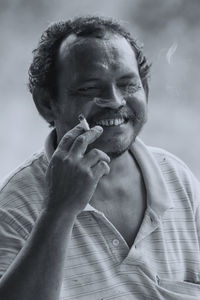 Close-up portrait of smiling man holding cigarette