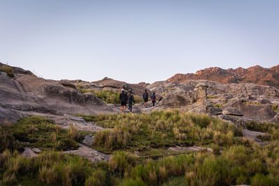 People on rocks against clear sky