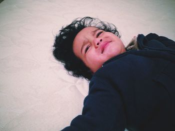 High angle view of boy crying on bed